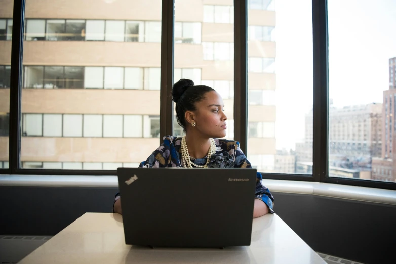 a woman sitting in front of a laptop computer, by Jessie Algie, pexels, renaissance, glass ceilings, aida muluneh, looking into the distance, photographed for reuters