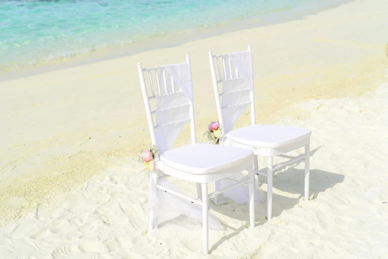 a couple of white chairs sitting on top of a sandy beach, on a white table, fully decorated, sidefx, pastel'