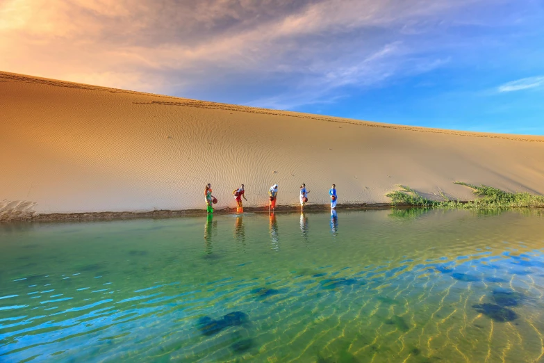 a group of people standing next to a body of water, a picture, inspired by Scarlett Hooft Graafland, pexels contest winner, land art, sand dune, shipibo, lush oasis, australia