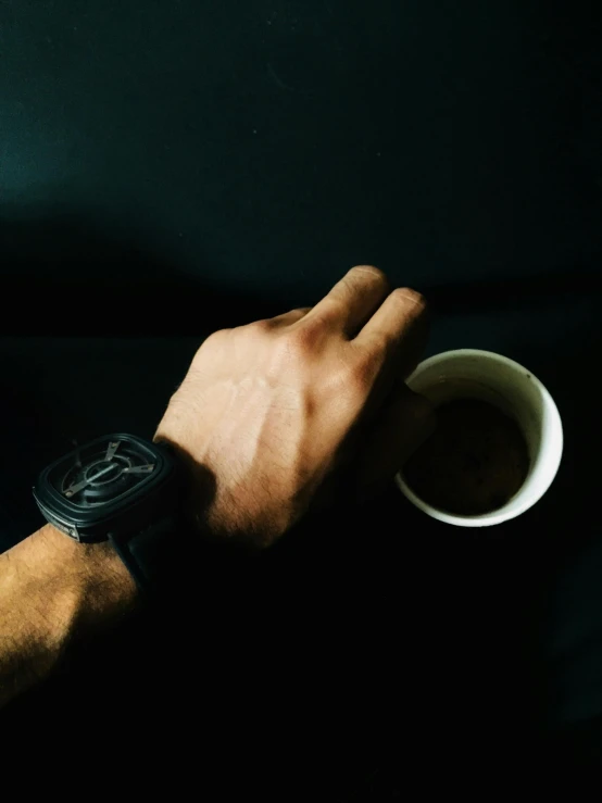 a close up of a person holding a cup of coffee, wearing a watch, black on black, hand gesture, uploaded