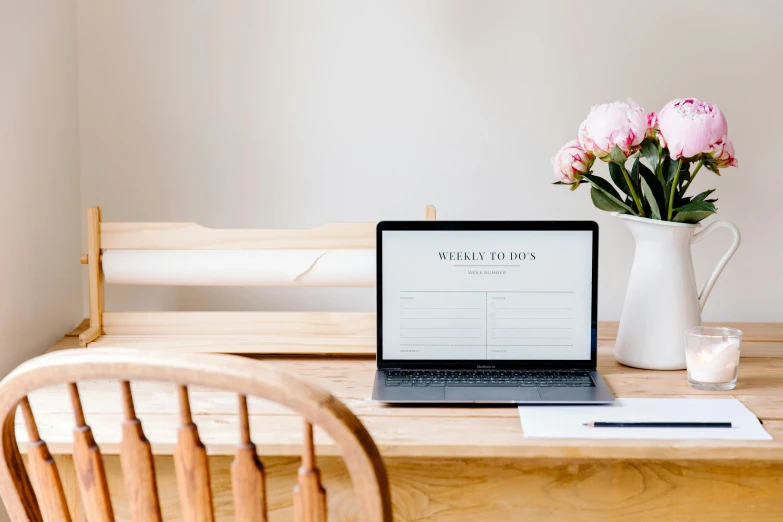 a laptop computer sitting on top of a wooden table, by Julia Pishtar, trending on pexels, minimalism, flowers around, well list, weekly, seated on wooden chair