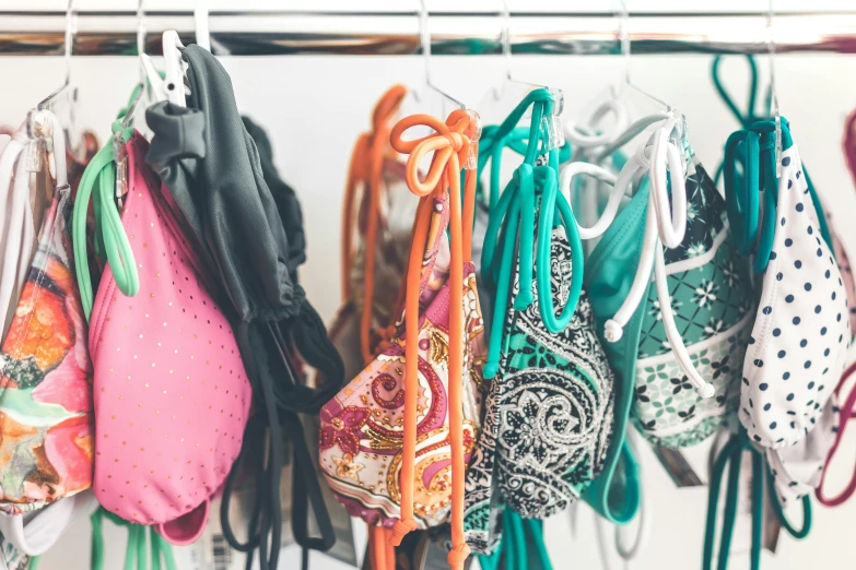 a bunch of bras hanging on a rack, a colorized photo, unsplash, monokini, patterned clothing, profile image, orange and teal color