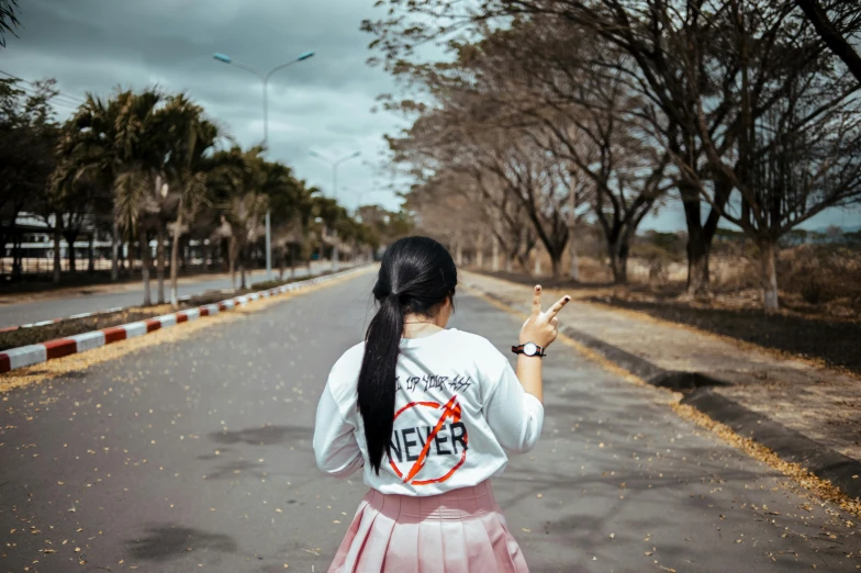 a woman standing in the middle of a road holding a cell phone, pexels contest winner, street art, white t-shirt with red sleeves, stop sign, no trees, nivanh chanthara