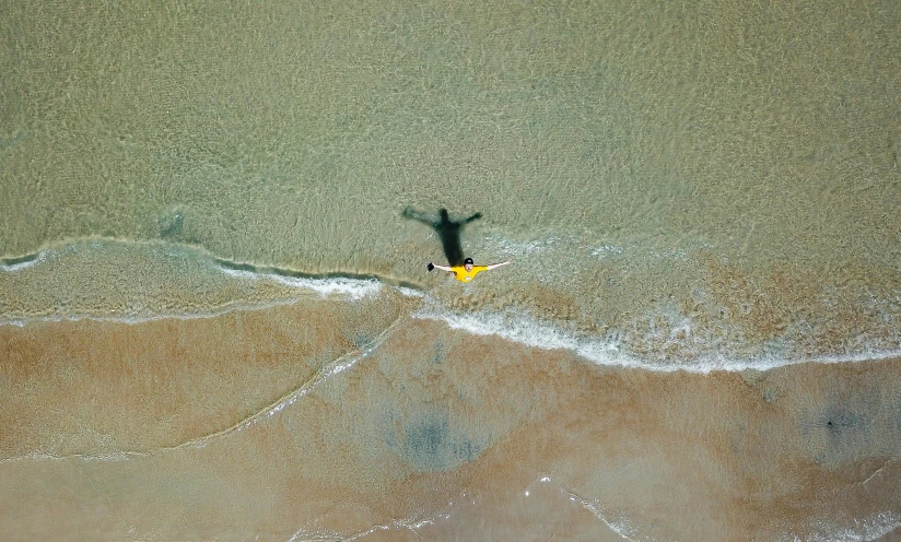 a person standing on a surfboard in the ocean, unsplash contest winner, minimalism, laying on sand, black and yellow, bird's eye, washed up