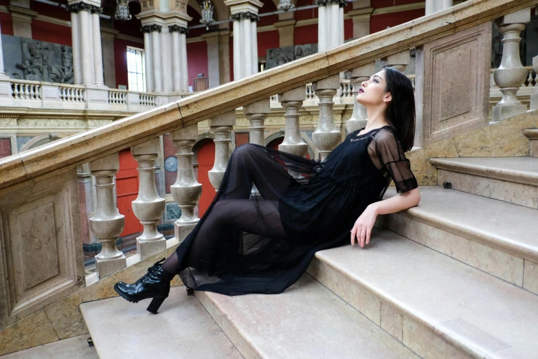 a woman sitting on the steps of a building, inspired by Adrienn Henczné Deák, pexels contest winner, baroque, wearing a gothic dress, dua lipa, sheer, francesca woodman style