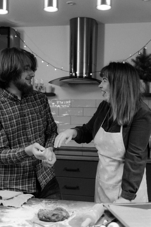 a black and white photo of two people in a kitchen, by Lucette Barker, festive, smiling at each other, matt berry, holding hands