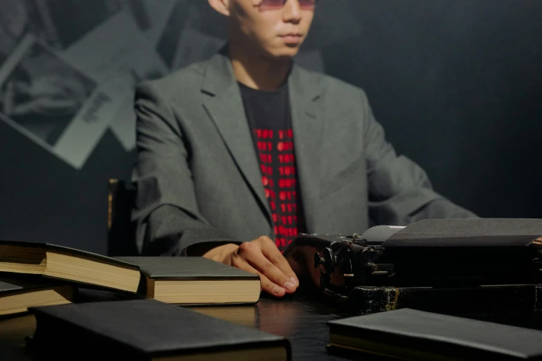 a man sitting at a table in front of a pile of books, an album cover, inspired by Yukihiko Yasuda, unsplash, secret agent, cinematic outfit photo, dark shades, typical cryptocurrency nerd