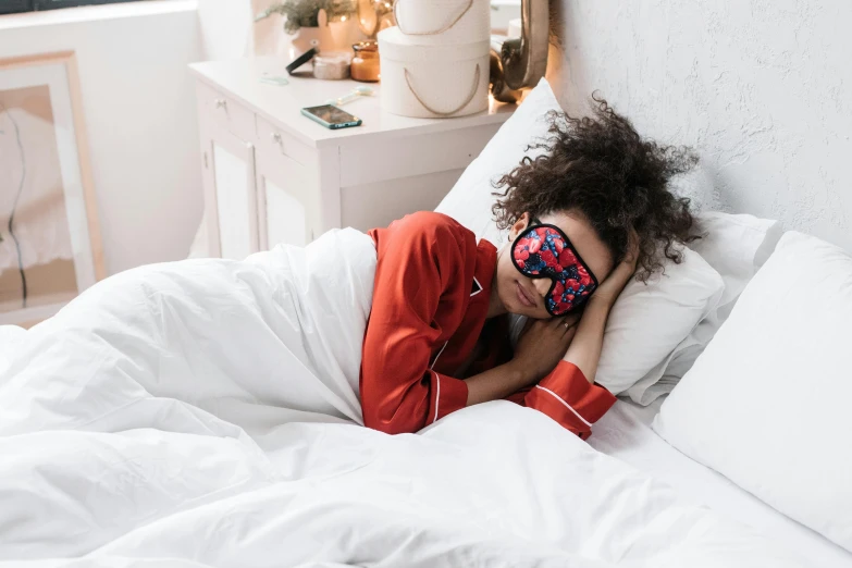 a woman laying in bed with a pair of eye glasses on her face, by Julia Pishtar, trending on pexels, happening, villain wearing a red oni mask, sleepwear, skincare, sleeping