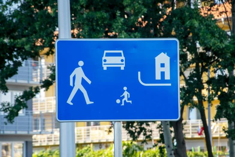 a blue street sign sitting on the side of a road, a poster, by Julia Pishtar, unsplash, people walking around, square, pictogram, cars and people