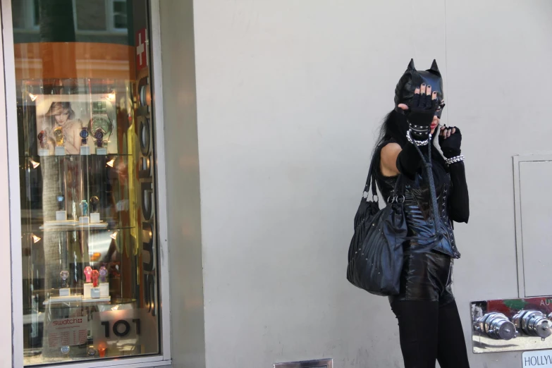 a woman in a cat mask talking on a cell phone, a photo, by Bernie D’Andrea, reddit, international gothic, exiting store, wearing studded leather, taken in the late 2010s, holding bat