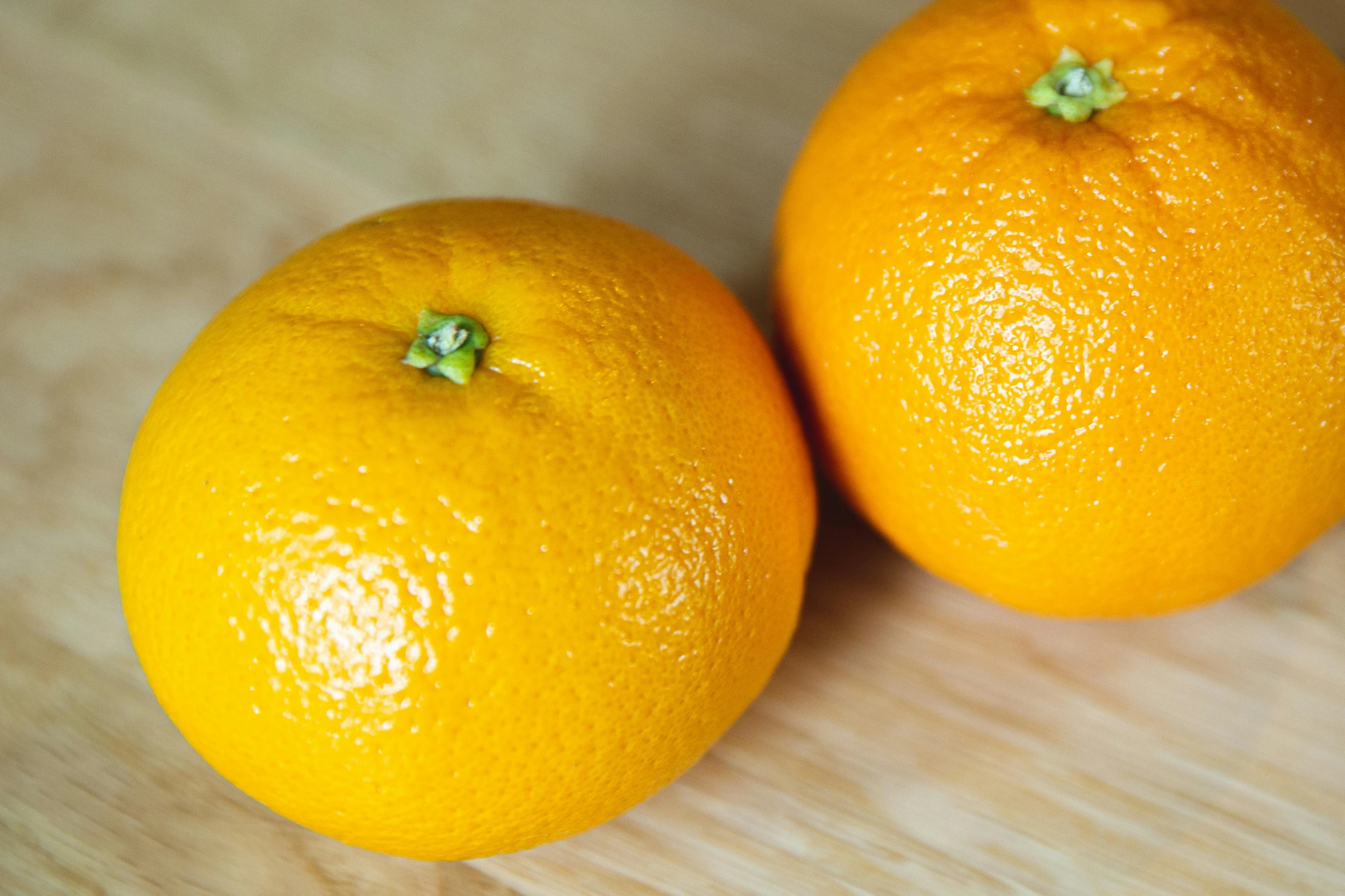 two oranges sitting next to each other on a table, over-the-shoulder shot, with round cheeks, zoomed in, top - down photograph