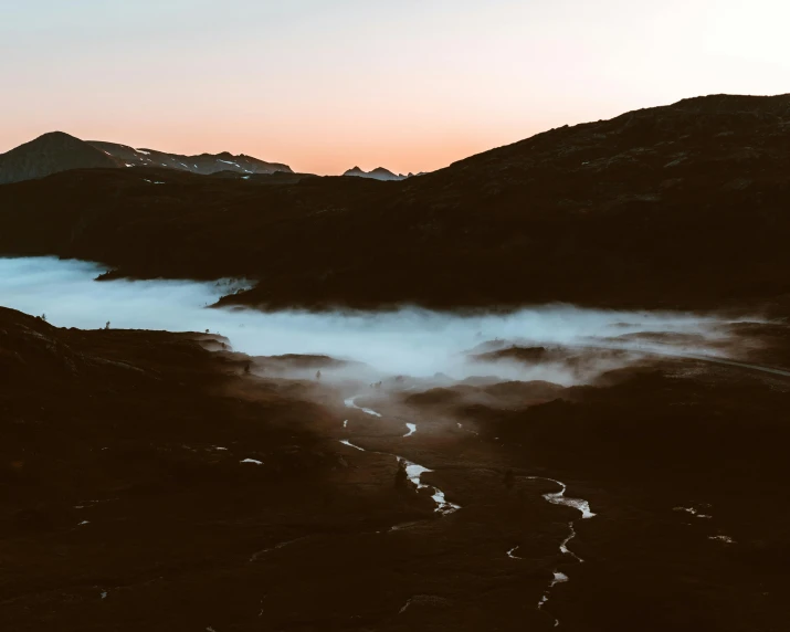 a group of people standing on top of a mountain, by Emma Andijewska, pexels contest winner, process art, water fog, background of a lava river, at dusk at golden hour, minimalistic aesthetics