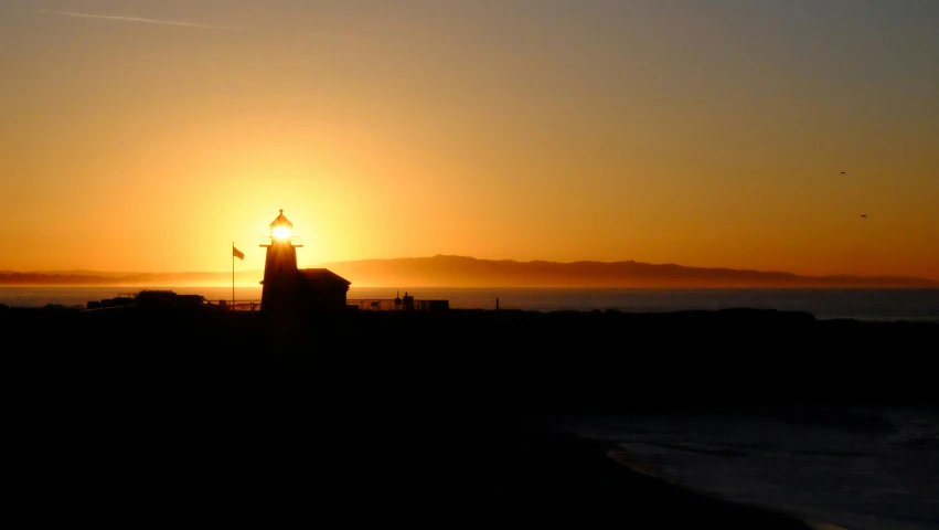 a lighthouse is silhouetted against the setting sun, a picture, by Robbie Trevino, long beach background, uploaded, profile, landscape photo