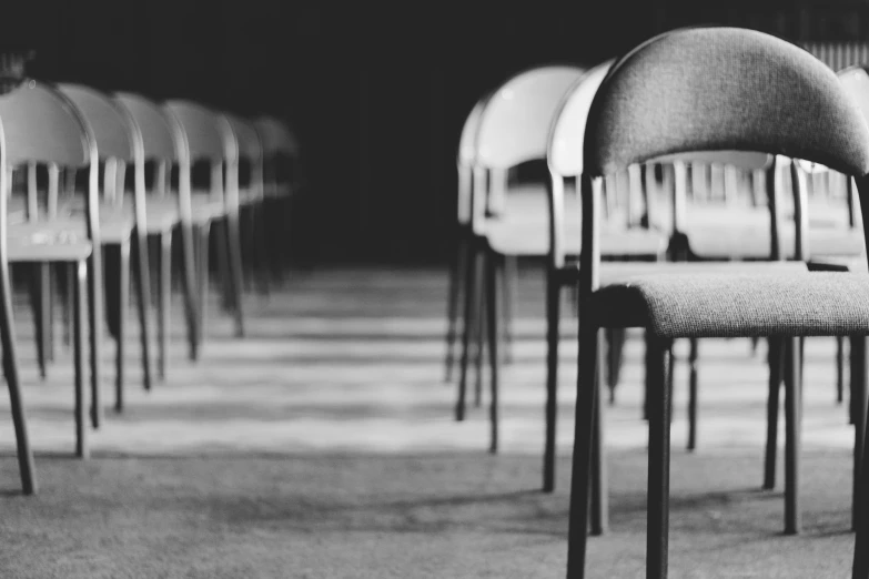 a black and white photo of a row of chairs, by Matija Jama, pexels, animation, tabernacle deep focus, he is all alone, student