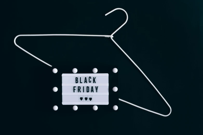 a black friday sign hanging on a clothes hanger, a black and white photo, pexels, hurufiyya, black 3 d cuboid device, costume, bralette, dark-skinned