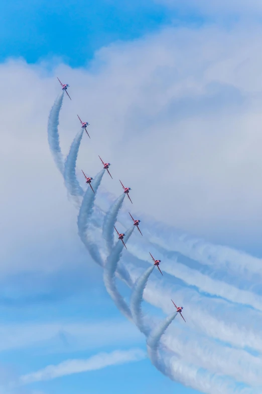 a group of airplanes flying through a blue sky, by Kev Walker, pexels contest winner, curved red arrow, scotland, smoke swirls, portrait shot