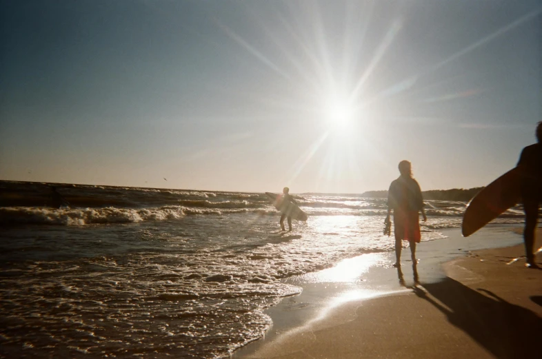 a group of people standing on top of a beach next to the ocean, surfing, profile image, two suns, shallow waters