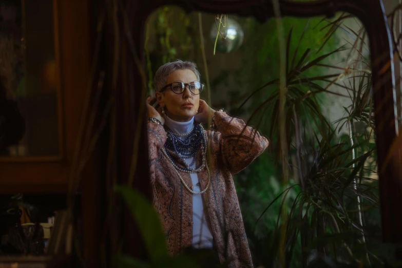 a woman standing in front of a mirror, inspired by Elsa Bleda, maximalism, garden behind the glasses, older woman, androgynous male, in jungle