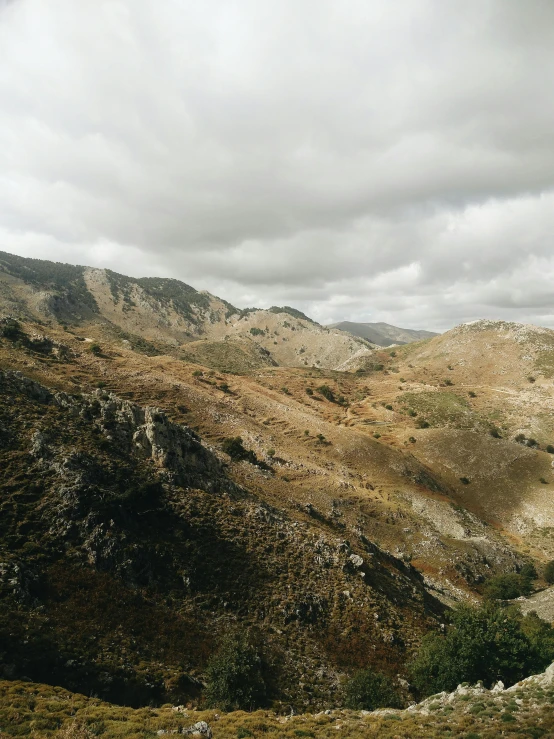 a man riding a horse on top of a lush green hillside, unsplash, les nabis, with lots of dark grey rocks, marbella landscape, overcast day, 4 k cinematic panoramic view