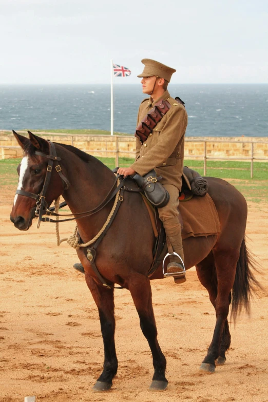 a man riding on the back of a brown horse, army uniform, bondi beach in the background, in 2 0 1 2, preserved historical