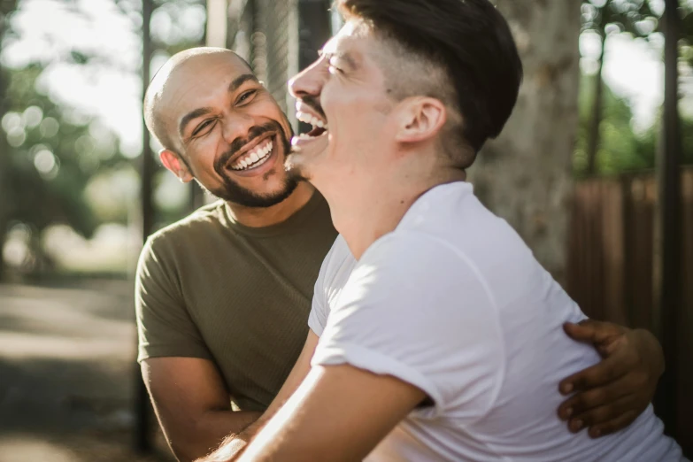 a couple of men sitting next to each other, pexels contest winner, kissing smile, two muscular men entwined, laughing your head off, mixed race