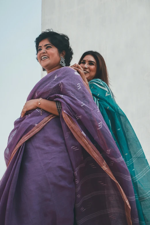 a group of women standing next to each other, pexels contest winner, bengal school of art, mauve and cyan, woman holding another woman, wearing a sari, overlooking