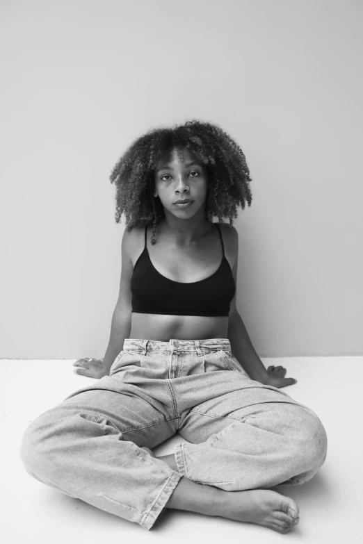 a black and white photo of a woman sitting on the floor, by Clifford Ross, pexels contest winner, black arts movement, wearing a crop top, sza, wearing only pants, wide eyed