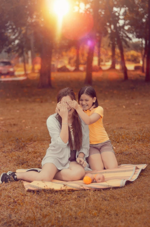 a woman and a little girl sitting on a blanket, a picture, by Lucia Peka, pexels contest winner, with instagram filters, orange hue, lesbian kiss, picnic
