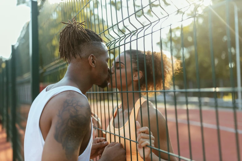 a couple kissing behind a fence on a tennis court, trending on pexels, afropunk, thumbnail, high quality image, ready to eat