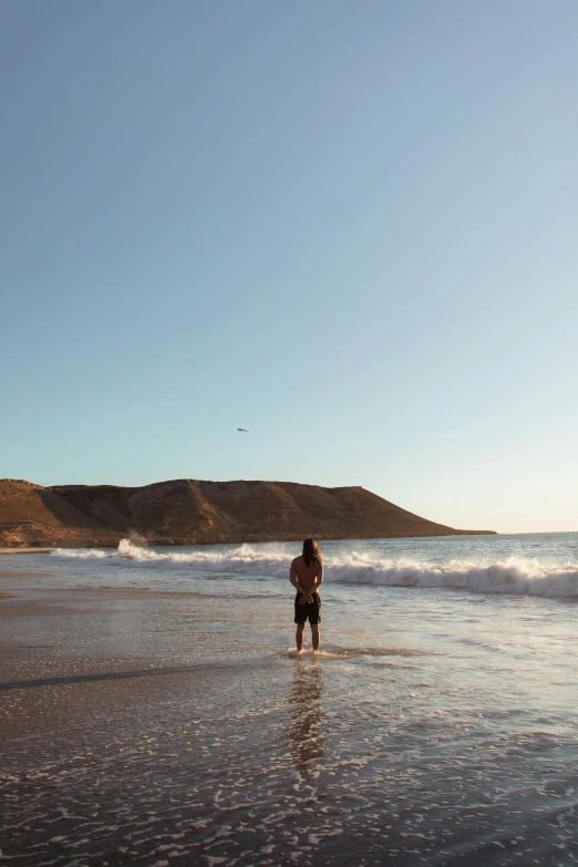 a man standing on top of a beach next to the ocean, hollister ranch, floating away, australian beach, kano)