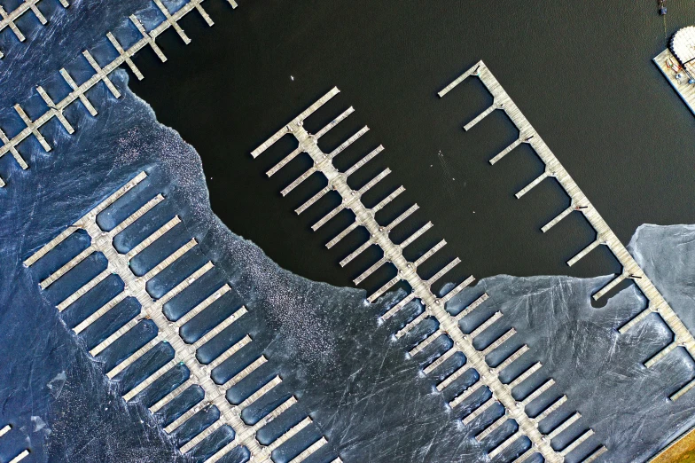 a large body of water next to a pier, a microscopic photo, inspired by Andreas Gursky, unsplash, generative art, industrial futuristic ice mine, metal bars, dutch angle from space view, concrete poetry