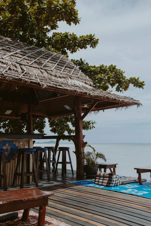 a gazebo sitting on top of a wooden deck next to a body of water, a portrait, unsplash, beach bar, thailand, slide show, half image