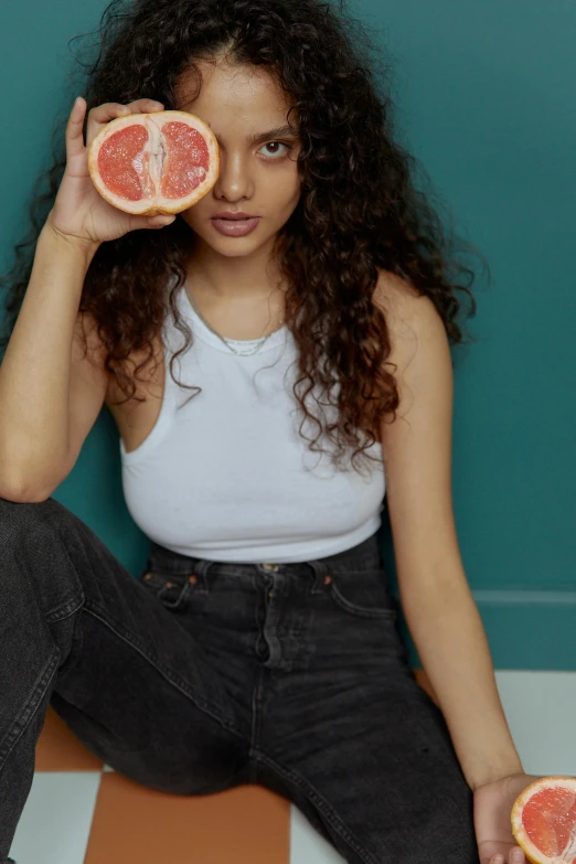 a woman sitting on the floor holding two grapefruits, trending on pexels, renaissance, imaan hammam, jeans, headshot, charli bowater