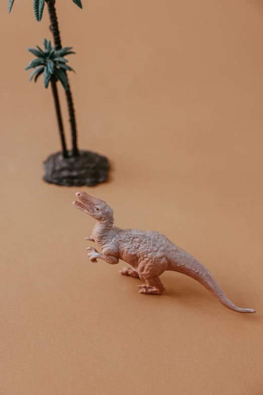 a toy dinosaur standing next to a palm tree, inspired by Adam Rex, trending on unsplash, 9 0 mm studio photograph tiny, terracotta, made of plastic, tabletop gaming