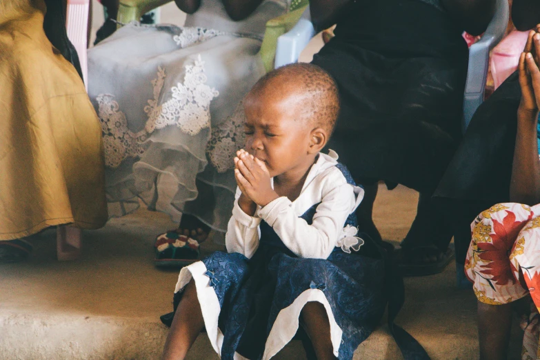 a small child sitting on the steps of a church, pexels contest winner, hurufiyya, closing her eyes, emmanuel shiru, holy ceremony, sickness