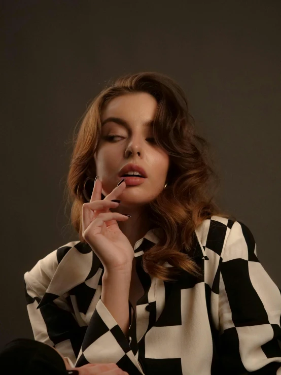 a woman sitting down with a cigarette in her mouth, inspired by Elsa Bleda, trending on pexels, photorealism, chequered cape, wavy shoulder-length hair, retro style ”, young beautiful amouranth