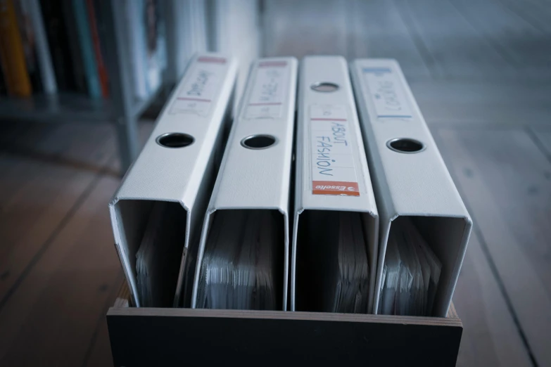 a couple of white boxes sitting on top of a wooden floor, an album cover, by Thomas Häfner, unsplash, shelf, confidential documents, racking focus, in a row