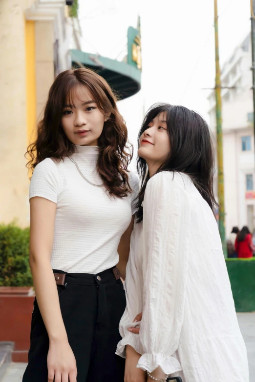 two women standing next to each other on a sidewalk, a picture, inspired by Wang Duo, trending on unsplash, in white turtleneck shirt, vietnamese woman, square, 8 k )