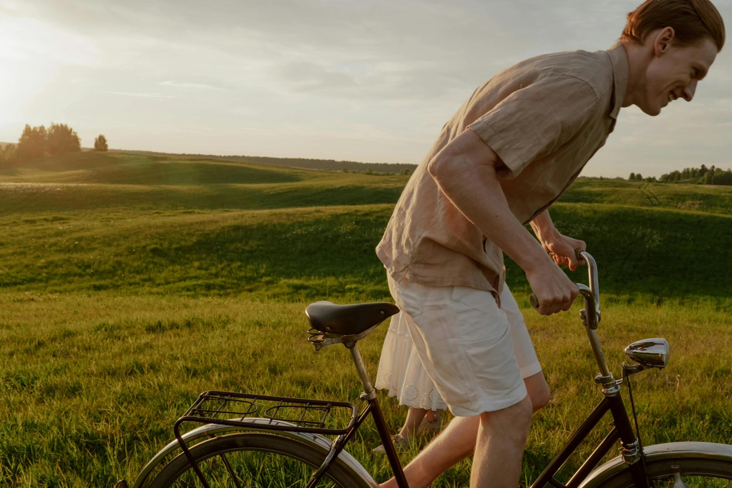 a man riding a bike across a lush green field, pexels contest winner, happening, man and woman walking together, summer evening, in australia, midsommar - t