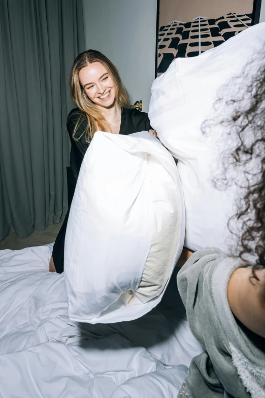 a woman holding a pillow on top of a bed, her friend, large and tall, product shot, light scatter