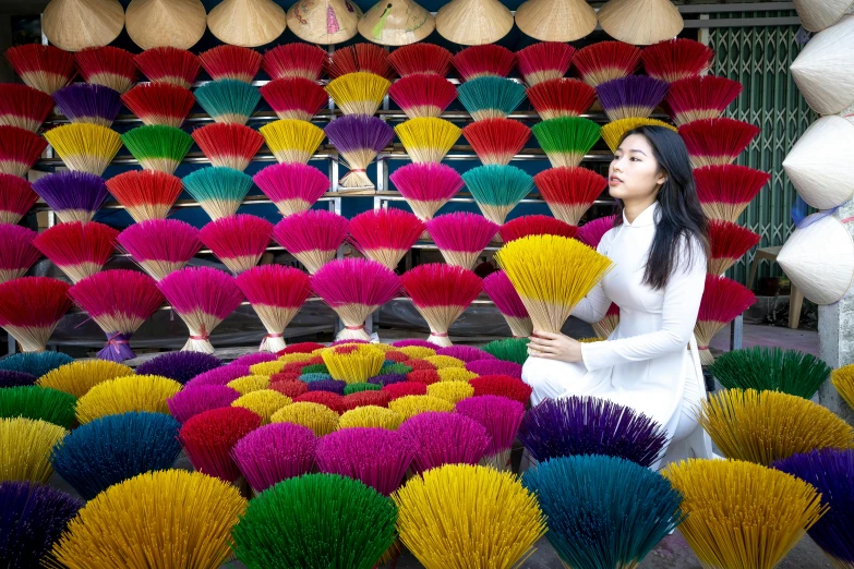 a woman standing in front of a display of colorful fan's, pexels contest winner, vietnamese temple scene, incense, ap, commercial photo