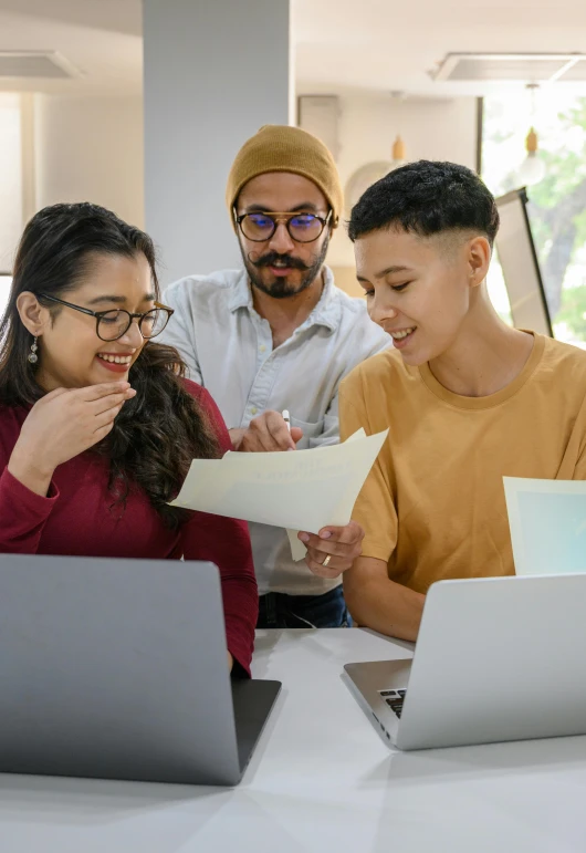 a group of people sitting around a table with laptops, trending on pexels, hypermodernism, lesbians, inspect in inventory image, ethnic origin, promotional image