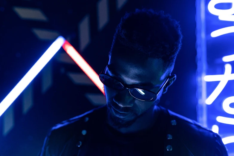 a man standing in front of a neon sign, pexels contest winner, afrofuturism, blue light saber, unreal engine : : rave makeup, man with glasses, mkbhd