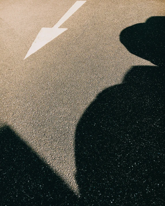 a shadow of a person riding a skateboard down a street, an album cover, by Attila Meszlenyi, trending on unsplash, postminimalism, arrow shaped, lgbtq, pointed face, on a road