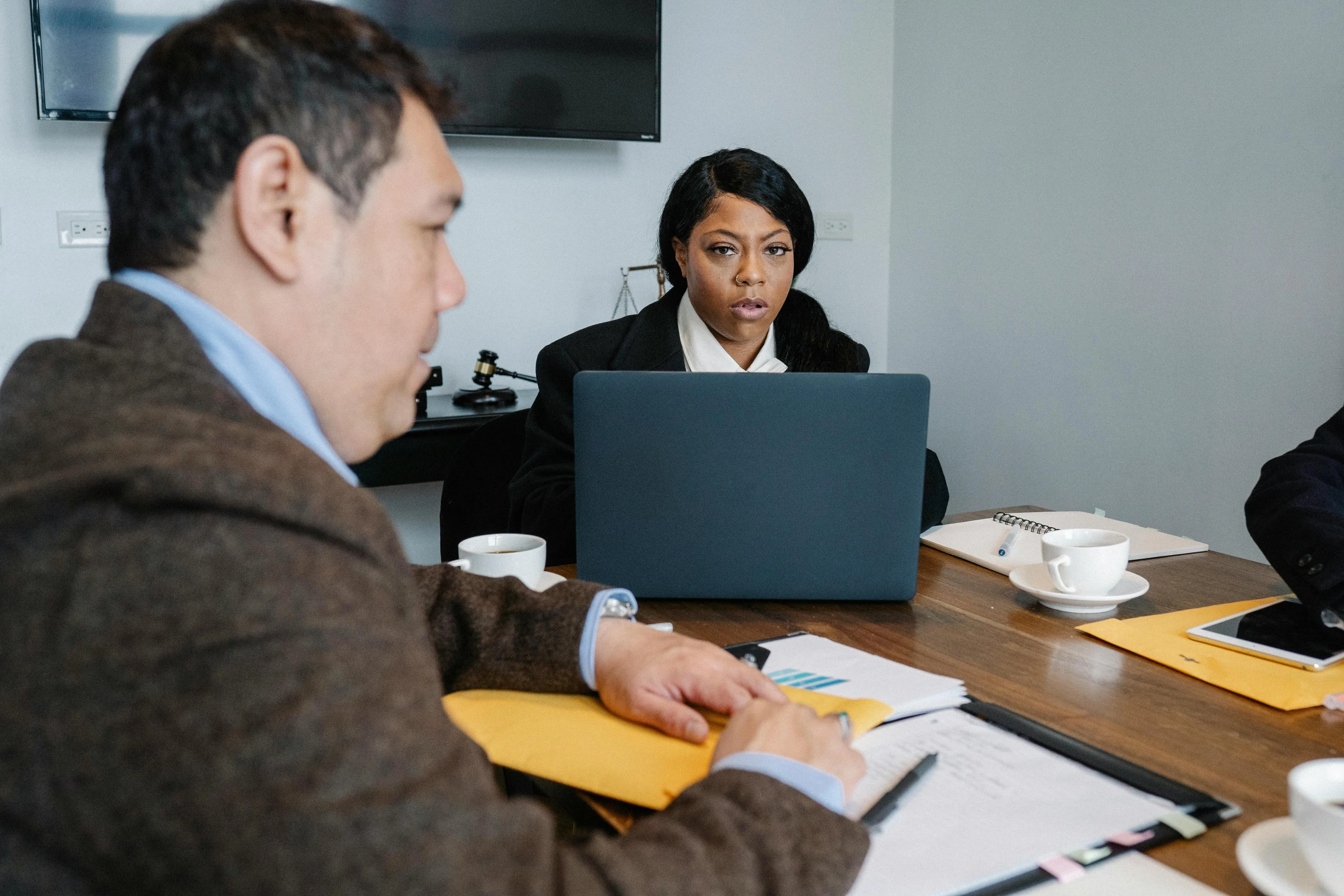 a group of people sitting around a wooden table, in front of a computer, female lawyer, profile image, thumbnail