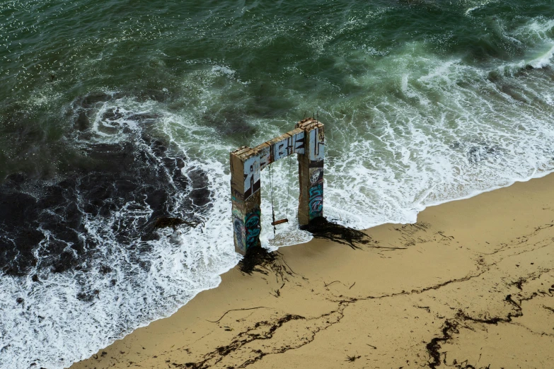 a couple of doors sitting on top of a sandy beach, an album cover, by Joe Stefanelli, pexels contest winner, environmental art, dredged seabed, air shot, giant waves, portal opening