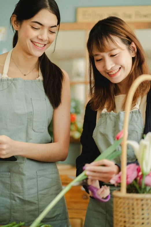 two women standing next to each other in a flower shop, by Sengai, trending on pexels, renaissance, white apron, thumbnail, wearing overalls, celebration