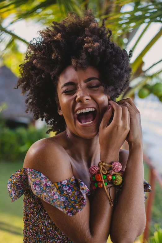 a woman laughing while holding a cell phone to her ear, trending on pexels, happening, tropical style, bracelets and necklaces, afro made of flowers, ad image