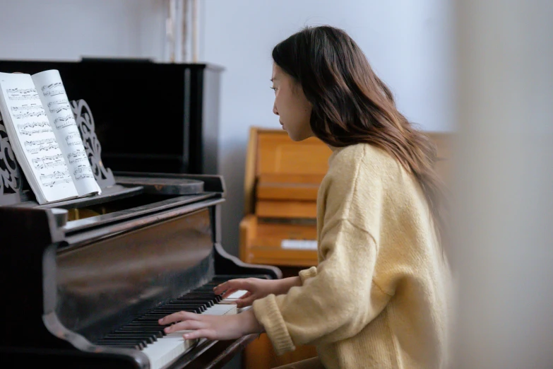 a woman in a yellow sweater playing a piano, inspired by Song Xu, pexels contest winner, mingei, documentary still, in a medium full shot, student, 奈良美智