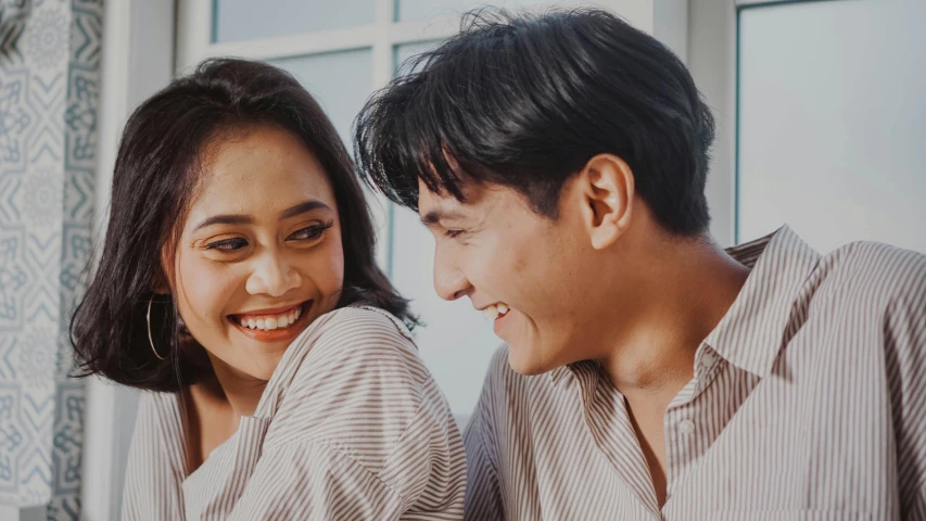 a man and a woman sitting next to each other, trending on pexels, smiling sweetly, asian female, background image, thumbnail